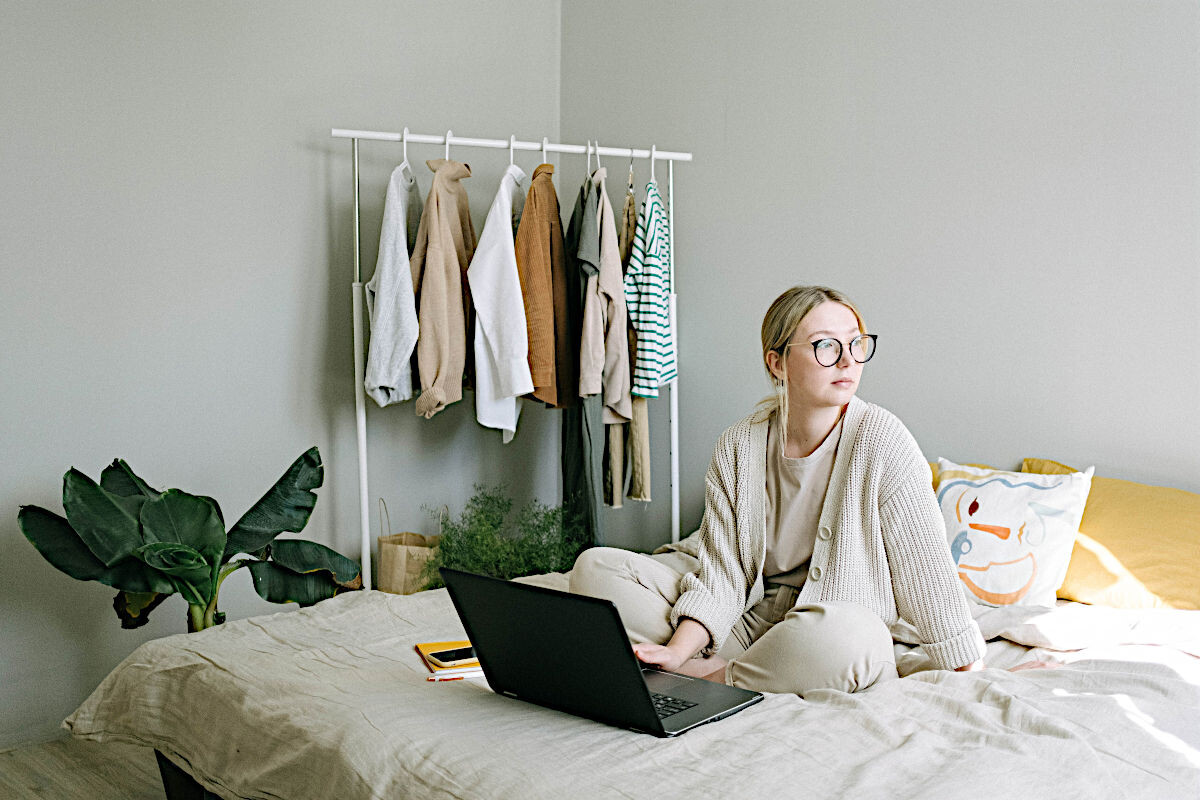 Dame sitzt mit Laptop in ihrem Bett im Schlafzimmer